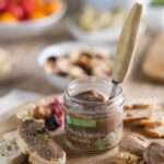Tarti rillettes de lentilles aux noix du Périgord ouvert avec couteau dans le bocal, tartine garnie et tranches de pain sur une planche en bois
