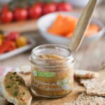 Bocal de tarti légumes soleil et cabécou ouvert, présenté sur une planche en bois avec une tartine gourmande à côté.