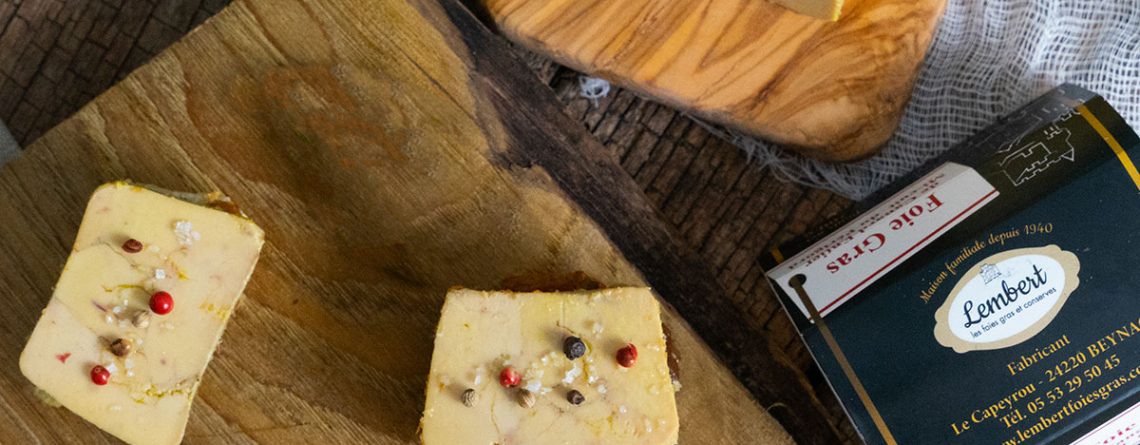 Tranches de foie gras de canard sur planche en bois, avec baies rouges et sel aromatisé