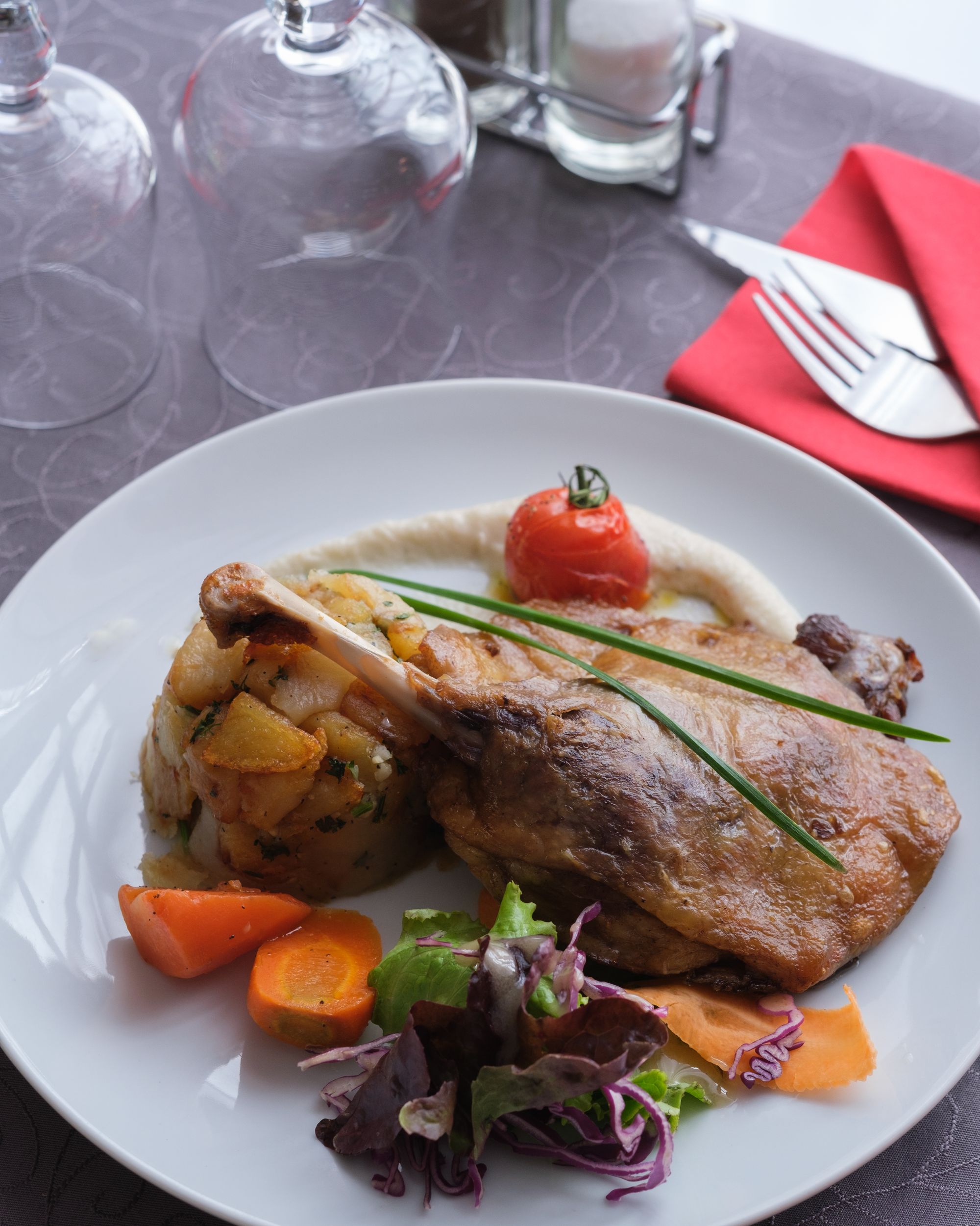 Confit de canard accompagné de pommes de terre cuisinées à la graisse de canard, légumes et tomates cerises