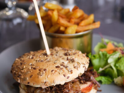 Burger au canard confit à Beynac, effiloché de canard, servi avec des frites maison et une petite salade colorée