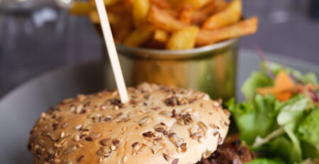 Burger au canard confit à Beynac, effiloché de canard, servi avec des frites maison et une petite salade colorée