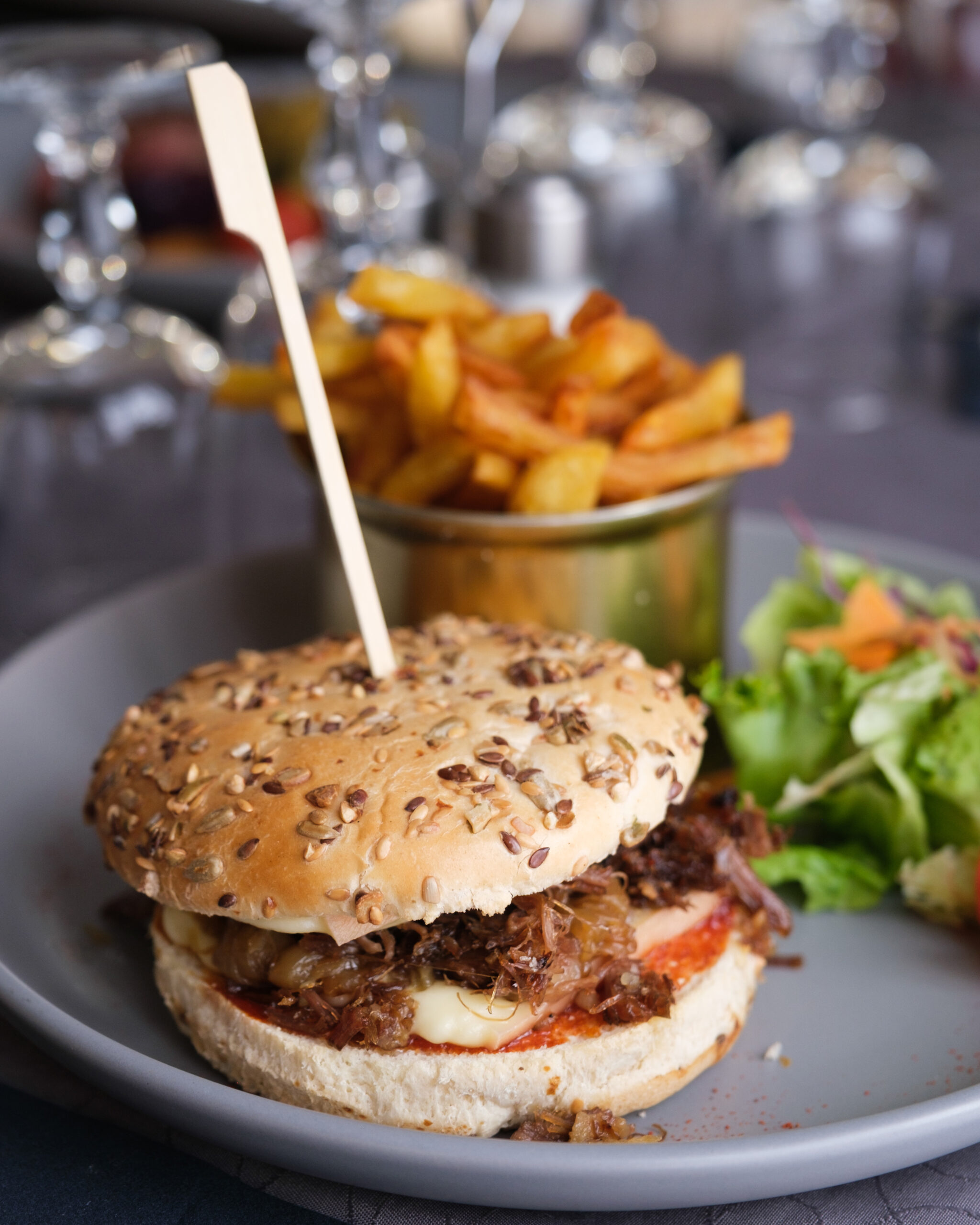 Burger au canard confit à Beynac, effiloché de canard, servi avec des frites maison et une petite salade colorée
