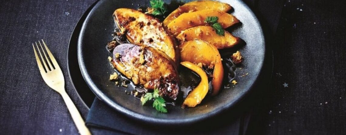 Recette foie gras à la poêle avec deux escalopes de foie gras poêlées servies dans une assiette noire accompagnées de légumes gourmands.