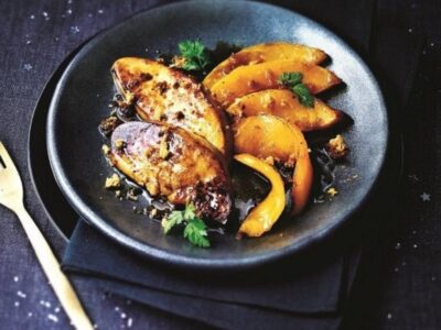 Recette foie gras à la poêle avec deux escalopes de foie gras poêlées servies dans une assiette noire accompagnées de légumes gourmands.