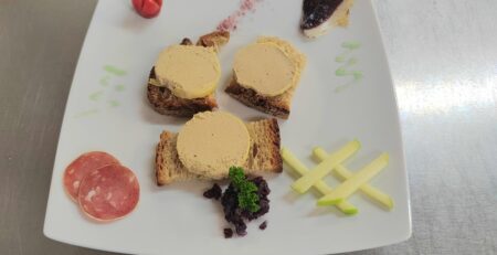 Trois médaillons de bloc de foie gras de canard servis sur pain de campagne avec magret séché, pomme verte et garnitures du terroir périgourdin.