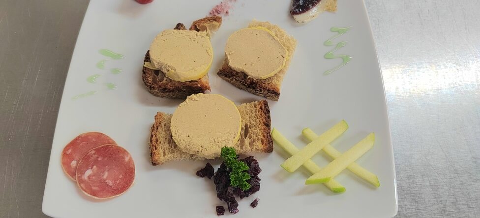 Trois médaillons de bloc de foie gras de canard servis sur pain de campagne avec magret séché, pomme verte et garnitures du terroir périgourdin.