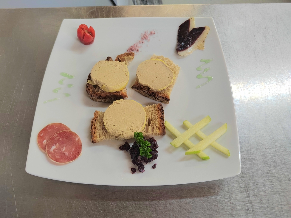 Trois médaillons de bloc de foie gras de canard servis sur pain de campagne avec magret séché, pomme verte et garnitures du terroir périgourdin.