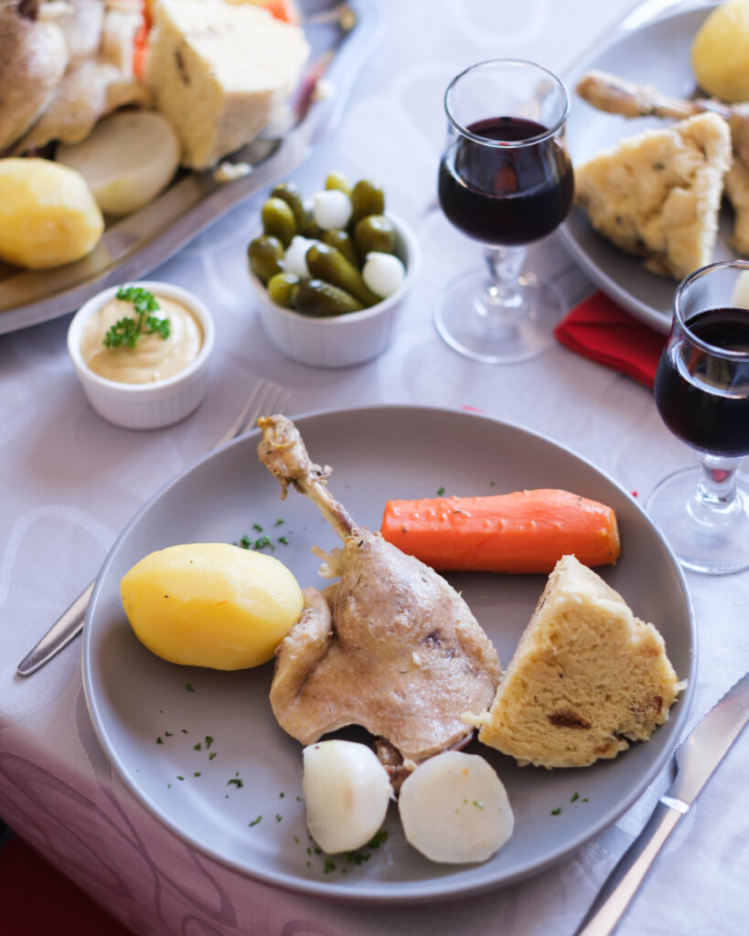 Assiette de confit de canard accompagné de mique traditionnelle et de petits légumes pour une expérience gourmande en Périgord.