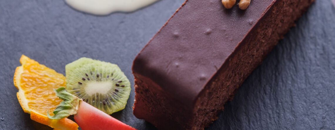 Gâteau aux noix nappé de chocolat servi à l’Auberge Maison Lembert avec crème anglaise et fruits frais