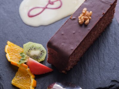 Gâteau aux noix nappé de chocolat servi à l’Auberge Maison Lembert avec crème anglaise et fruits frais