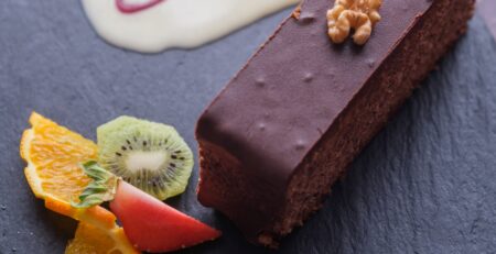 Gâteau aux noix nappé de chocolat servi à l’Auberge Maison Lembert avec crème anglaise et fruits frais