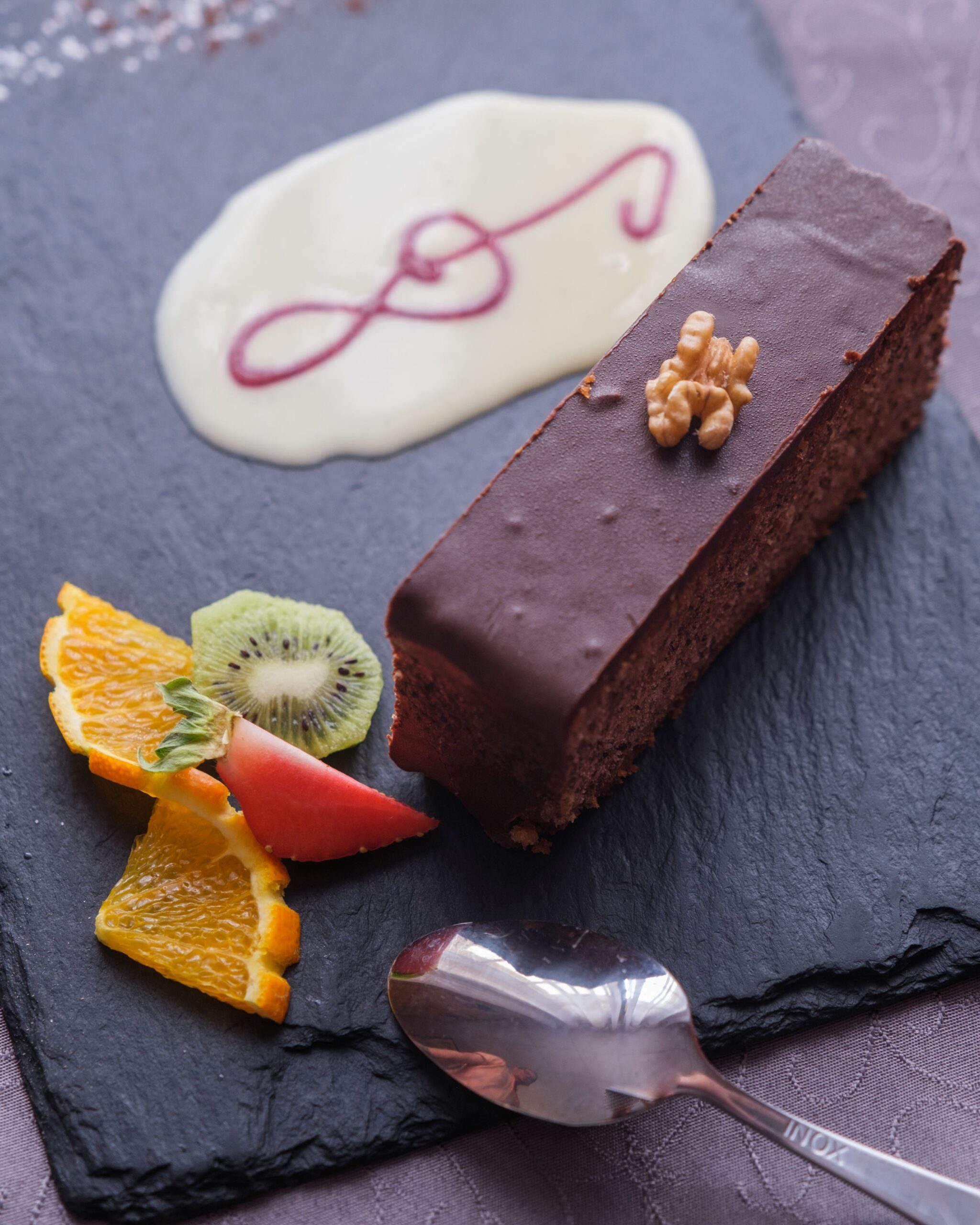 Gâteau aux noix nappé de chocolat servi à l’Auberge Maison Lembert avec crème anglaise et fruits frais
